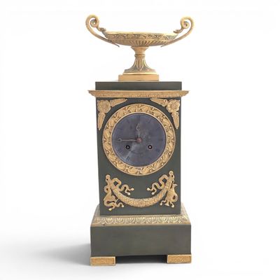 a black and gold clock on a stand with a bowl on top of it