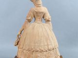statue of a woman in a dress and hat on a wooden base