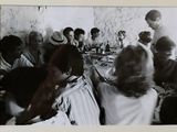 photographie en noir et blanc représentant un groupe de personnes assises autour d'une table