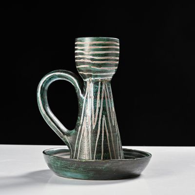 un vase vert et blanc posé sur une assiette, sur une table