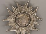 an antique silver sunburst with a coin in the middle of it
