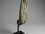 a bronze statue of a praying hand on a black stand