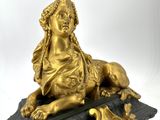 a gold statue of a woman laying on top of a table