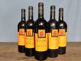 six bottles of wine are lined up on a wooden table