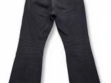 Ce jean est noir et comporte une fermeture éclair sur le côté.