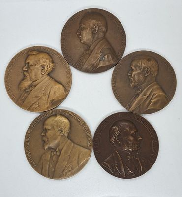quatre médailles de bronze représentant des hommes en costume-cravate sur un fond blanc
