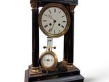 a black and gold clock on a stand on a white background