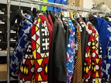 many shirts hanging on a rack in a room