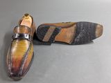 pair of men ' s shoes on a grey surface with one shoe in the middle