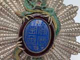 silver broochle with a blue stone surrounded by a green dragon