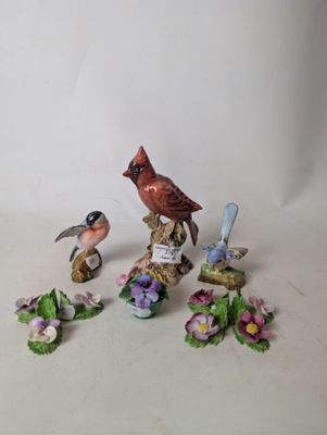 several figurines of birds and flowers on a white surface