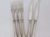 four forks and a knife on a white surface
