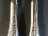 a pair of silver plated knives with floral designs on them