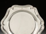 a silver plate with a scalloped edge on a white surface