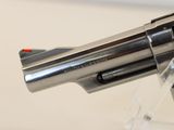 a silver revolver with a red handle on a clear stand