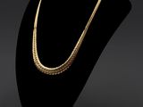 un collier en or posé sur un socle de mannequin noir