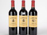 trois bouteilles de vin rouge posées l'une à côté de l'autre sur une surface blanche