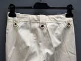 the white pants are hanging on a hanger against a gray wall