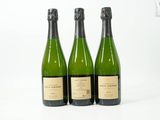 trois bouteilles de vin posées les unes à côté des autres sur une surface blanche