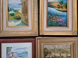 four paintings on the wall of a room, one of which has a clock on it