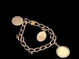 a close up of a gold bracelet with coins on a black background
