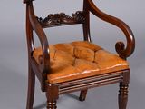 an antique wooden chair with a leather seat on a grey background