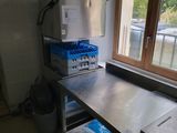 une cuisine équipée d'une table en inox et d'un réfrigérateur