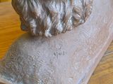 une statue représentant un homme barbu assis sur une table