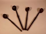 four wooden spoons are sitting on a white surface next to each other