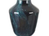 un vase bleu posé sur une surface blanche