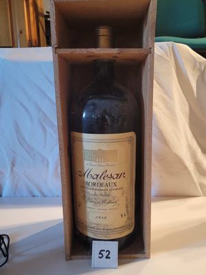une bouteille de vin dans un coffret en bois posé sur un lit