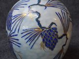 a blue and white vase with pinecones on it