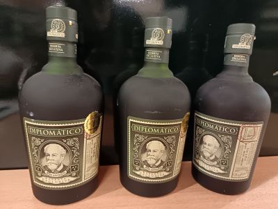 trois bouteilles de rhum posées sur un comptoir, à côté d'un sac noir