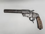 gros plan d'un pistolet avec un manche en bois sur une surface blanche