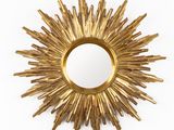 miroir doré à rayons de soleil sur un mur blanc, avec un fond blanc