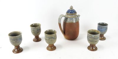 five cups and a pitcher sitting next to each other on a table