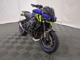 une photo d'une moto bleue et jaune garée sur un sol à damier noir et blanc