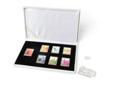 une boîte blanche contenant six timbres, posée sur une surface blanche
