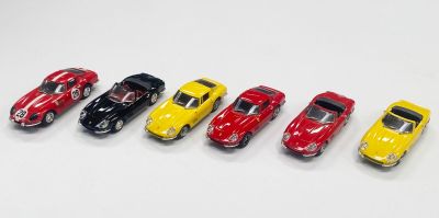 Six petites voitures sont alignées en rang sur une surface blanche.