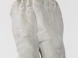 a white sculpture of a foot with two hands on it