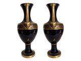 pair of black and gold vases sitting on top of a white surface
