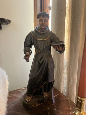 a statue of a monk on a table next to a candle