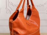 an orange leather bag sitting on top of a wooden table