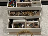 un sac à main en or posé par terre à côté d'un coffret à bijoux