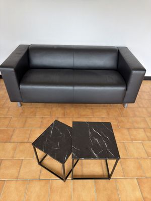 un canapé en cuir noir et deux tables dans un salon