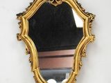 un miroir doré sur un mur blanc, avec un fond noir