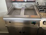 une cuisine équipée d'une cuisinière, d'un évier et d'un tableau accroché au mur