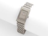 une montre en argent posée sur une serviette blanche
