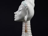 a white vase that has a head on top of it