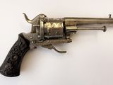 un revolver en argent avec une poignée en bois sur une surface blanche